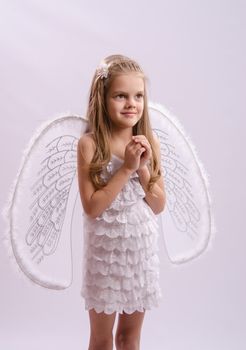 Six year old girl in a bright angel costume with wings on a white background