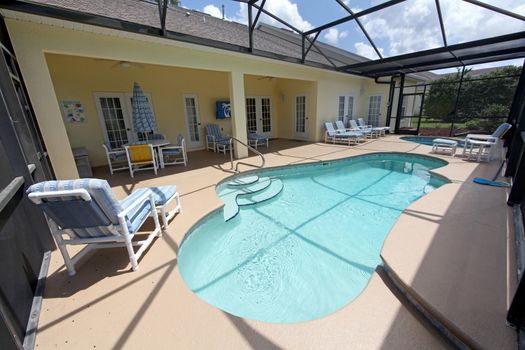 A Swimming Pool, Spa and Lanai with chairs