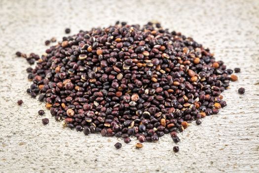 a pile of gluten free black quinoa grain on rustic wood
