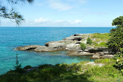 Bermuda coast with aqua blue tropical waters and rock formations complete with small caves.