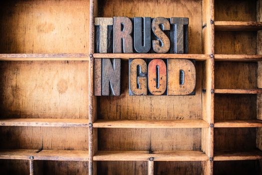 The words TRUST IN GOD written in vintage wooden letterpress type in a wooden type drawer.