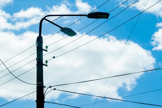 wires and lantern on blue cloudy sky background 