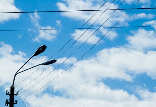 wires and lantern on blue cloudy sky background 