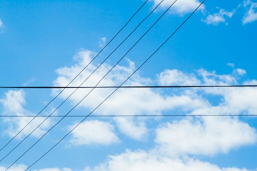 crossing wires on blue cloudy sky background 