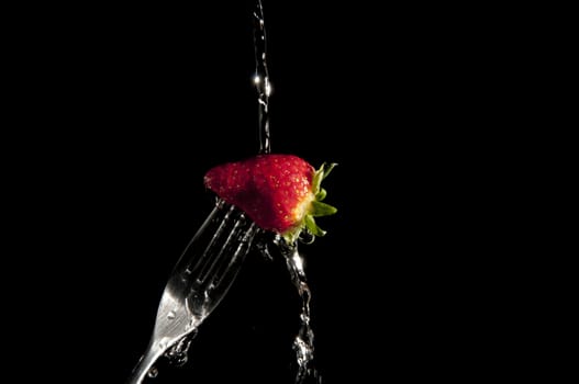 red strawberry on a fork with black background