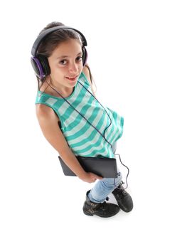 High angle picture for a beautiful pre-teen girl using a tablet computer and headphones. White background