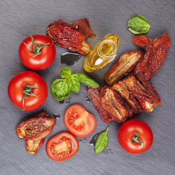 Sundried and fresh tomatoes with fresh basil leaves on stone background, top view. Culinary italian eating.