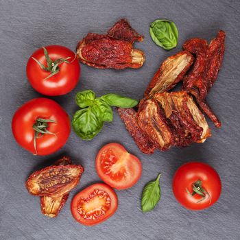 Sundried and fresh tomatoes with fresh basil leaves on stone background, top view. Culinary italian eating.