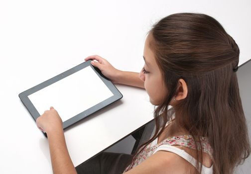 Beaitiful pre-teen girl using a tablet computer. High angle. Clipping path for the screen