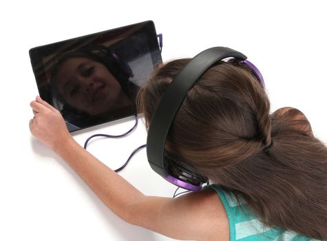 Beautiful pre-teen girl on the floor, usin a tablet computer and headphones, white background