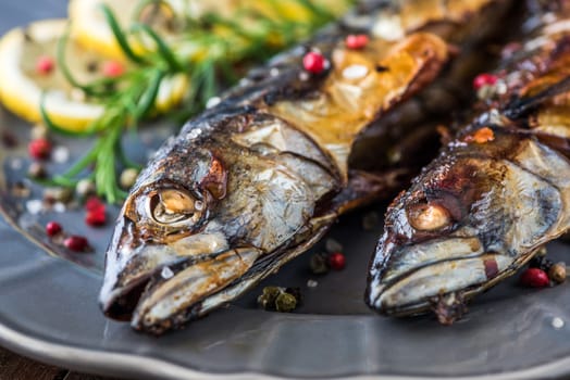 Baked Whole Mackerel Fish with Spice, Lemon and Rosemary on a Plate on Wooden Table