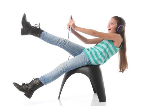 Beautiful pre-teen girl going crazy with a tablet computer and headphones. Isolated