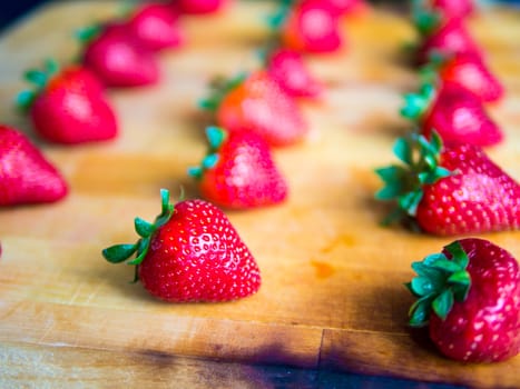 Arranged rows of strawberries on a wooden board