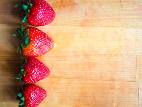 Arranged row of strawberries on a wooden board with empty space