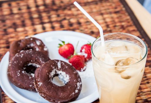 Sugar chocolate donuts and fresh strawberries and ice coffee