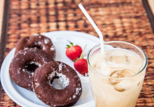 Sugar chocolate donuts and fresh strawberries and ice coffee