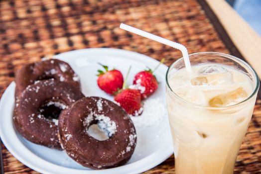 Sugar chocolate donuts and fresh strawberries and ice coffee