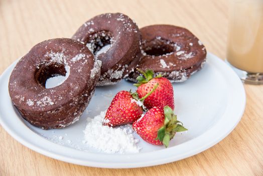 Sugar chocolate donuts and fresh strawberries and ice coffee