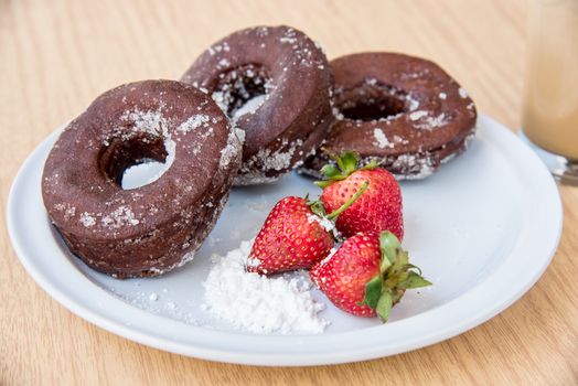Sugar chocolate donuts and fresh strawberries and ice coffee