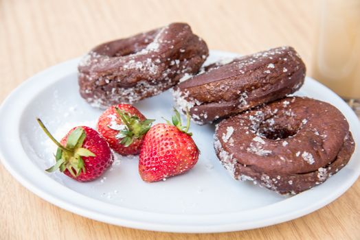 Sugar chocolate donuts and fresh strawberries and ice coffee