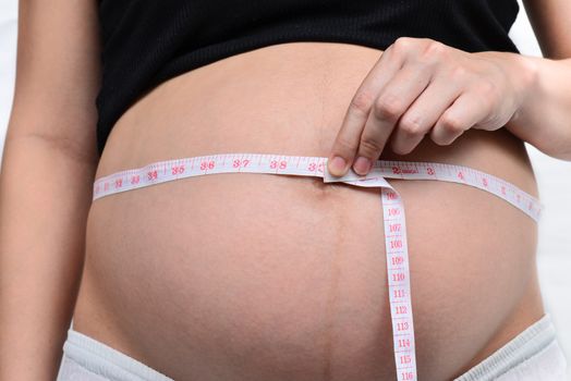 Woman holding her pregnant belly. White background.