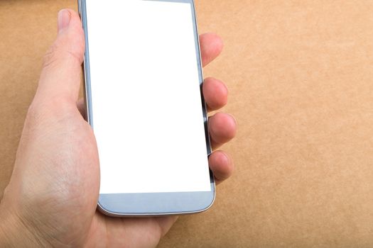 Close up view of mobile phone holding in hand with blank white screen, on wooden table.