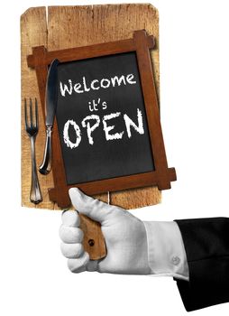 Hand of waiter with glove holding a cutting board and blackboard with silver cutlery and text, welcome it is open. Isolated on white background