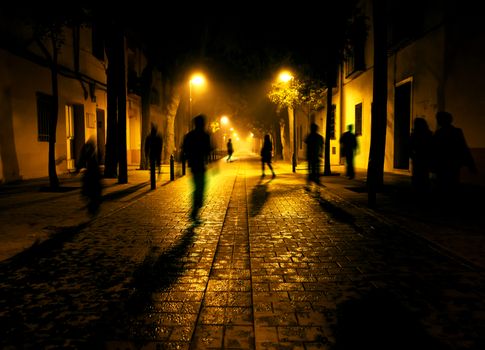 City at night. Shadows of people walking down the street