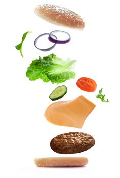 Burger ingredients falling into place to create a sandwich over a white background 