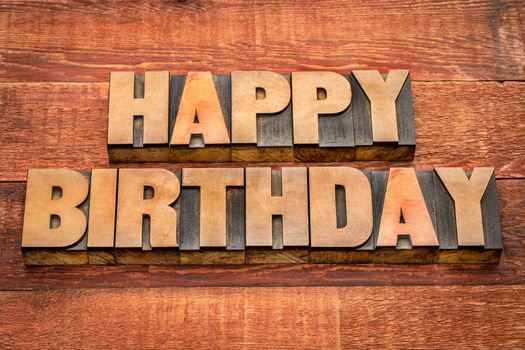 Happy Birthday greetings in letterpress wood type against rustic, red painted barn wood