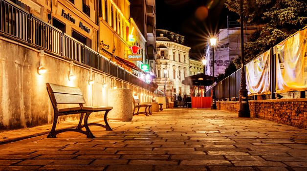 Bucharest old city center by night with bench on narrow street.