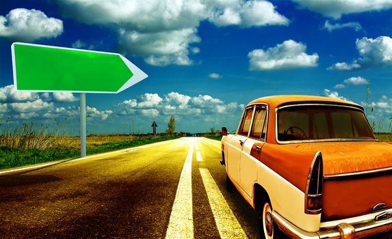 Vintage car on shiny road with traffic arrow sign.