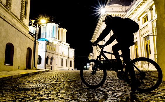 Night scene with shadow of a back packer cyclist on old street in Bucharest.