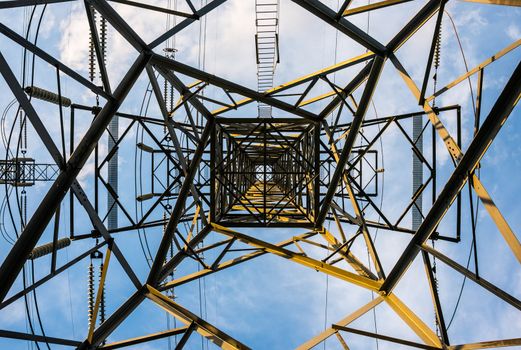 Straight up view from directly beneath a tall transmission tower.