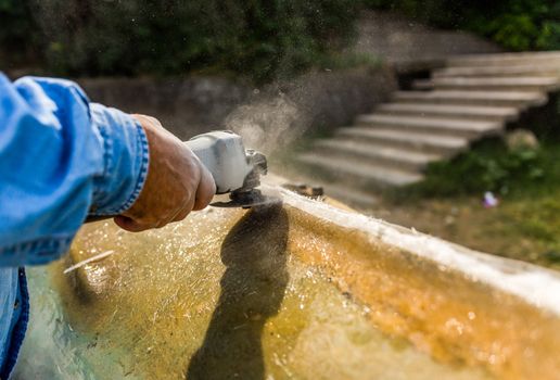 Hand of a worker polishing boat made of resin.