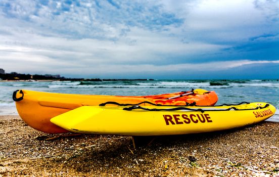 Orange and yellow rescue boats on the sea shore.