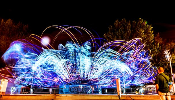 Night scene at luna park with rotating machine lights.