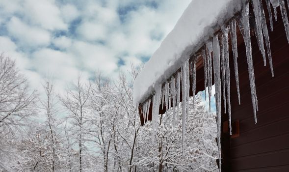 Snow and icicles on cabin roof eaves