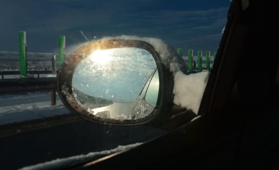 Winter highway with car mirror.