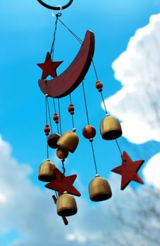 Moon and stars wind chimes with blue sky background.