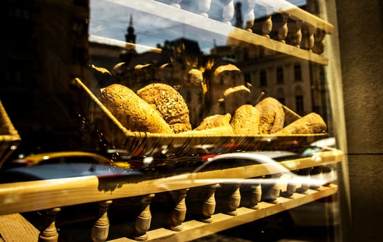 Bakery window with a bread basket and city reflection.