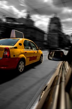 Yellow cab chased by black car in motion blur speed traffic.