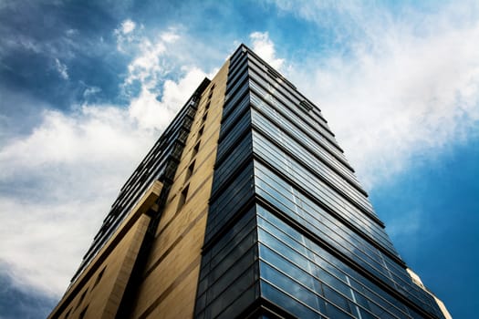 Blue office building under blue white sky.