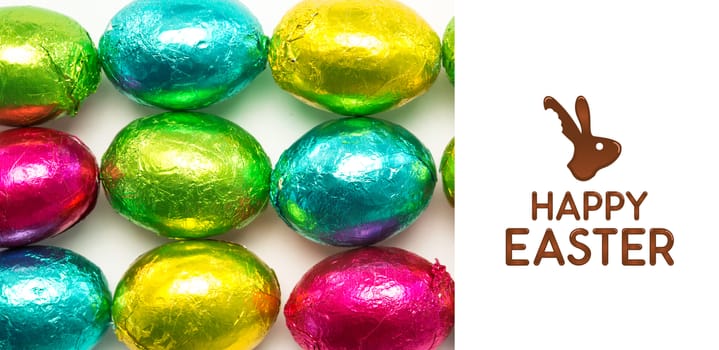 happy easter graphic against colourful foil wrapped easter eggs overhead shot