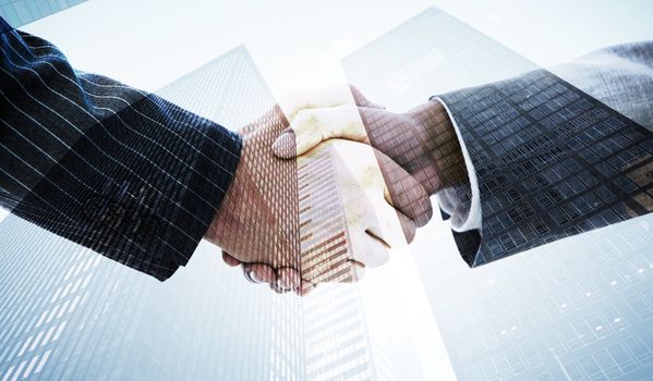 Business people shaking hands against skyscraper