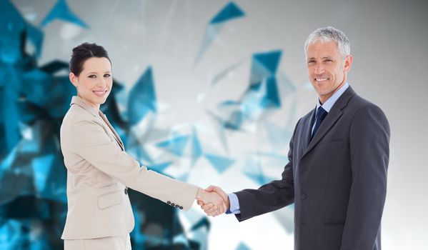 Smiling business people shaking hands while looking at the camera against angular design