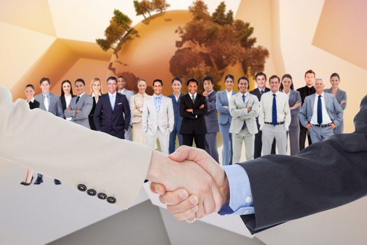 Smiling business people shaking hands while looking at the camera against globe on abstract background