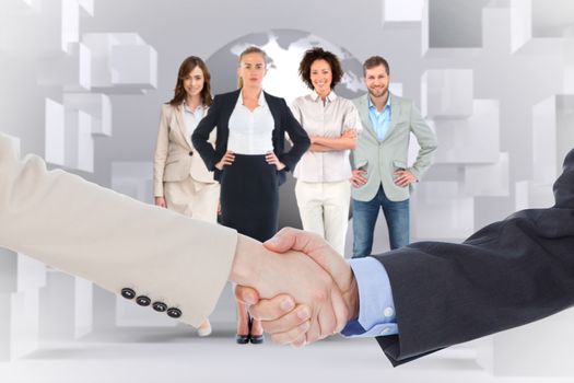 Smiling business people shaking hands while looking at the camera against planet on grey background with cubes