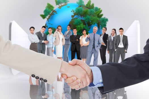 Smiling business people shaking hands while looking at the camera against earth on abstract grey background
