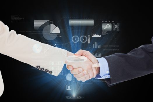 Smiling business people shaking hands while looking at the camera against technology interface